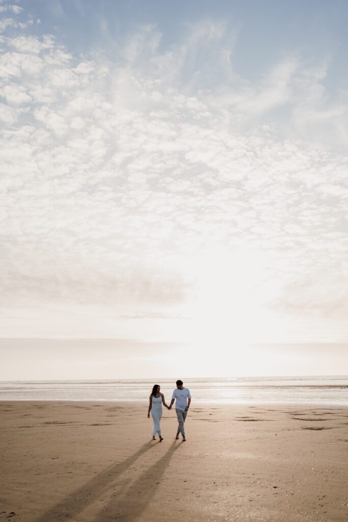 Walking along the beach at sunset on their engagement shoot