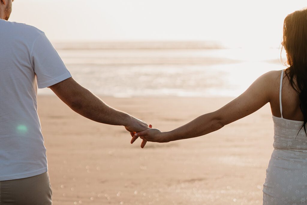 Photograph of the couple holding hands at sunset